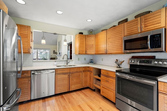 kitchen featuring decorative light fixtures, sink, decorative backsplash, appliances with stainless steel finishes, and light hardwood / wood-style floors