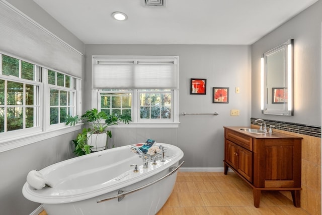 bathroom featuring tile patterned flooring, vanity, and a tub to relax in