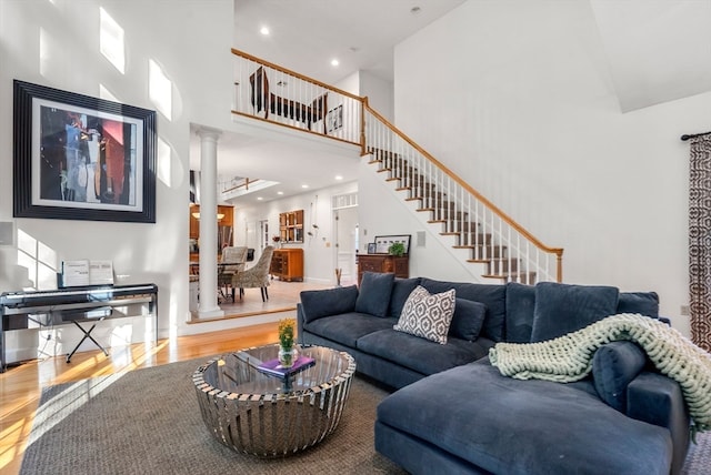 living room featuring decorative columns, hardwood / wood-style flooring, and a towering ceiling