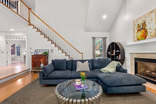 living room featuring high vaulted ceiling, a tiled fireplace, and hardwood / wood-style flooring