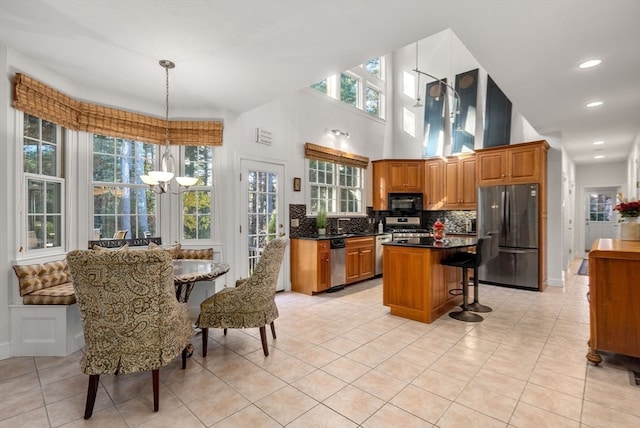 kitchen with appliances with stainless steel finishes, a center island, decorative light fixtures, and light tile patterned floors