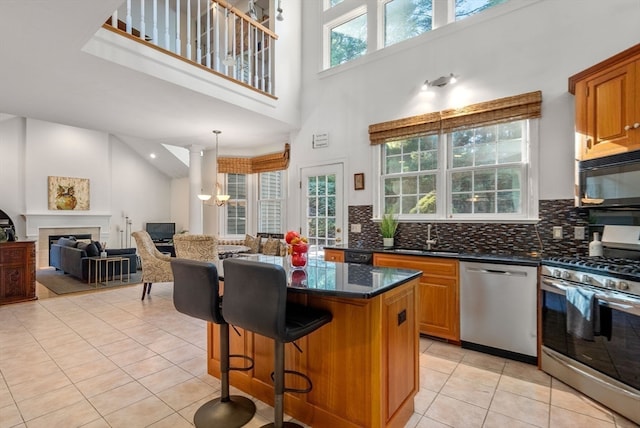 kitchen featuring stainless steel appliances, a center island, sink, a breakfast bar, and a high ceiling