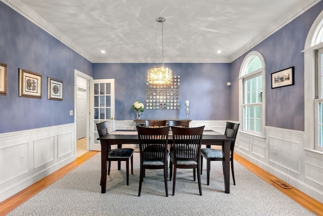 dining area with light hardwood / wood-style flooring, a notable chandelier, and crown molding