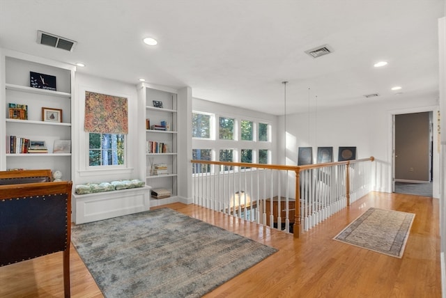 hallway featuring built in shelves and hardwood / wood-style floors