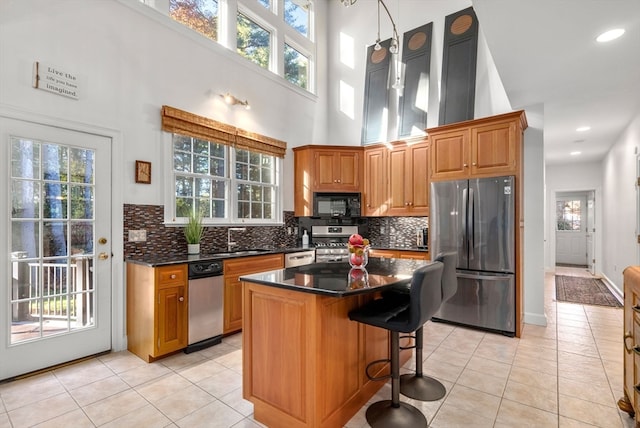 kitchen featuring a towering ceiling, stainless steel appliances, light tile patterned flooring, and a kitchen island