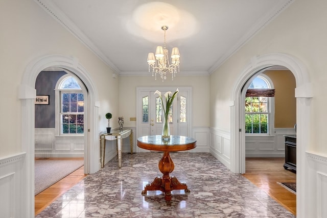 entrance foyer featuring a chandelier, a healthy amount of sunlight, and crown molding