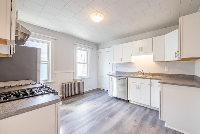 kitchen featuring a sink, radiator, appliances with stainless steel finishes, and white cabinetry