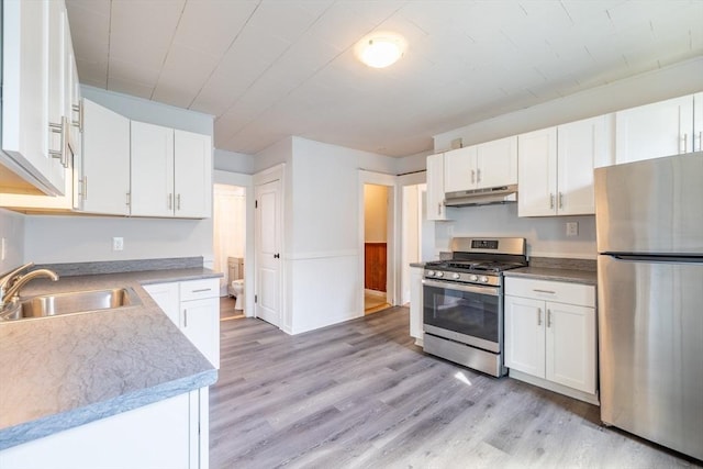 kitchen with white cabinets, a sink, stainless steel appliances, light wood-type flooring, and under cabinet range hood