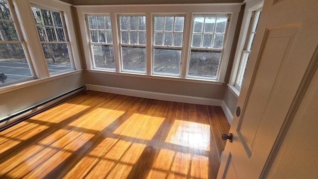 empty room with baseboards, a baseboard heating unit, and light wood-style flooring