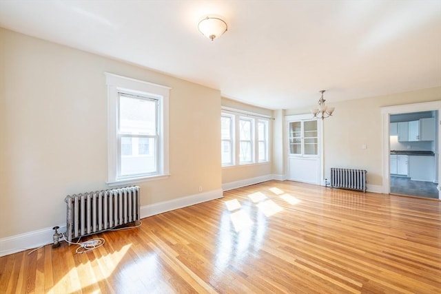 unfurnished room with baseboards, a chandelier, radiator heating unit, and light wood-style flooring
