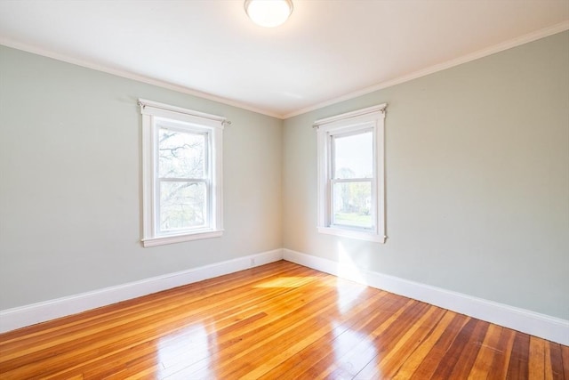 empty room featuring crown molding, baseboards, and light wood finished floors