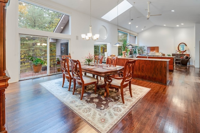 dining room featuring high vaulted ceiling, a skylight, ceiling fan with notable chandelier, and dark hardwood / wood-style flooring