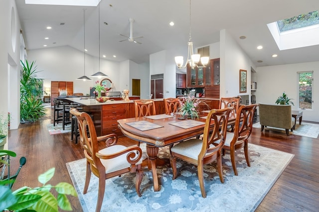 dining area featuring dark hardwood / wood-style floors, high vaulted ceiling, and a skylight