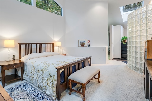 carpeted bedroom with high vaulted ceiling and a skylight