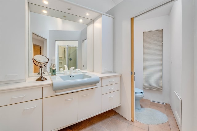 bathroom with vanity, toilet, tile patterned floors, and a shower with shower door