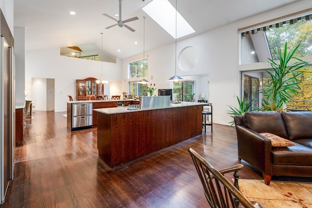 kitchen featuring hardwood / wood-style floors, hanging light fixtures, a kitchen island, high vaulted ceiling, and a skylight