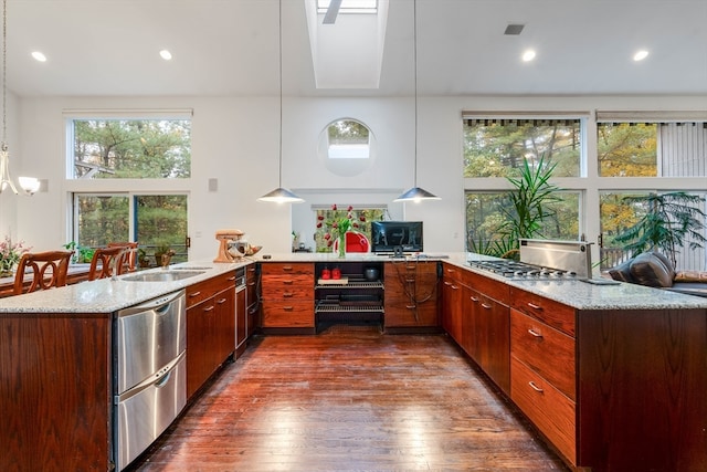 kitchen with dark hardwood / wood-style floors, kitchen peninsula, sink, decorative light fixtures, and light stone counters