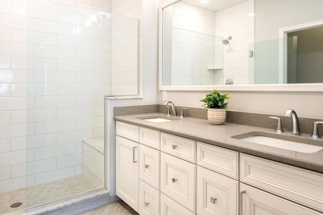 full bath with double vanity, tiled shower, and a sink