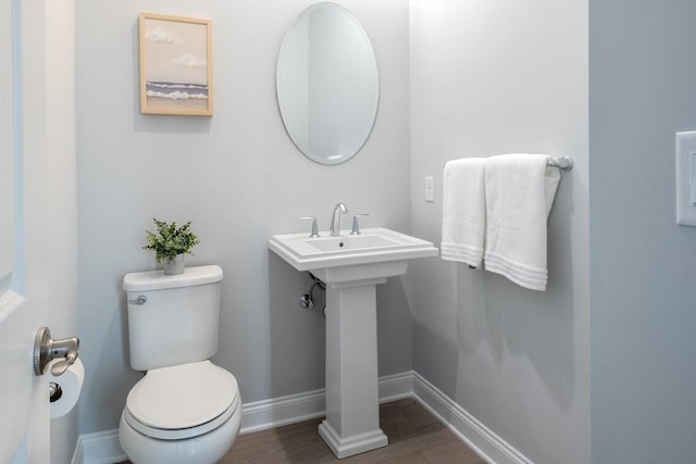 bathroom featuring toilet, a sink, baseboards, and wood finished floors