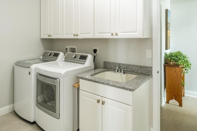 clothes washing area featuring cabinet space, baseboards, a sink, and independent washer and dryer