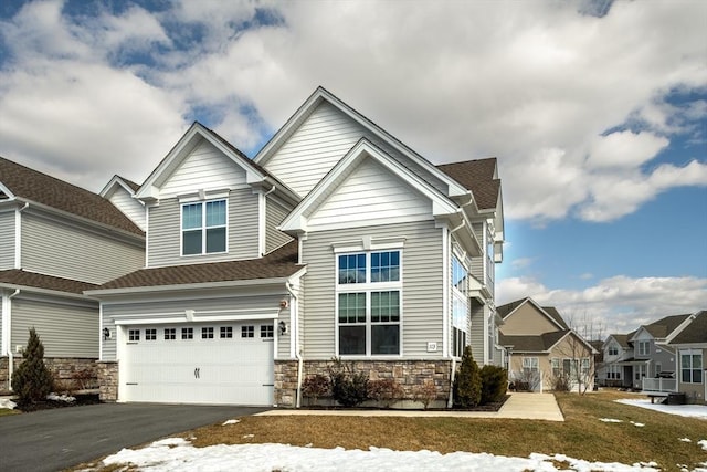 view of front facade with aphalt driveway, a residential view, stone siding, and an attached garage