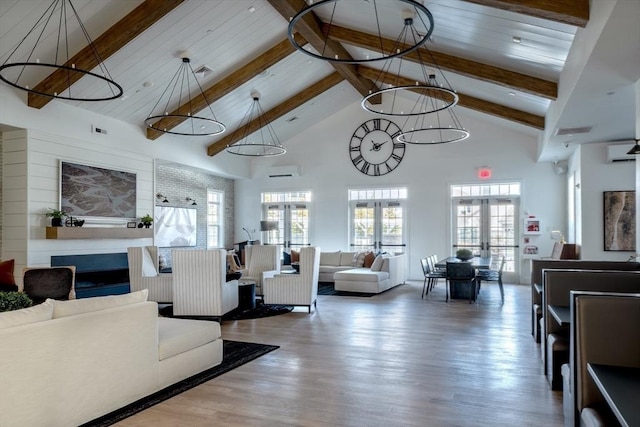 living area featuring high vaulted ceiling, wood finished floors, french doors, a wall mounted AC, and beam ceiling