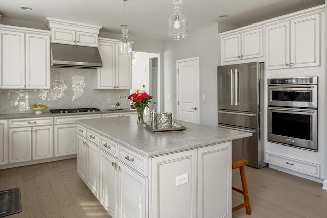 kitchen featuring under cabinet range hood, stainless steel appliances, white cabinetry, backsplash, and light wood finished floors