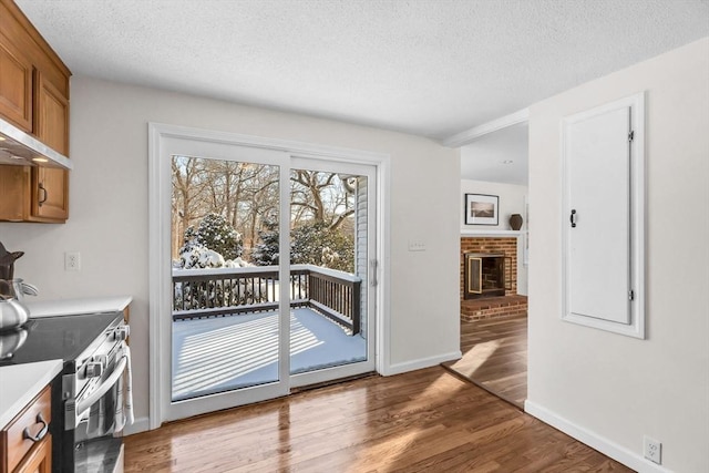 doorway featuring hardwood / wood-style flooring, a textured ceiling, and a brick fireplace