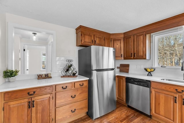 kitchen with decorative backsplash, sink, appliances with stainless steel finishes, and light wood-type flooring