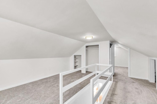 additional living space with vaulted ceiling, built in shelves, and light carpet