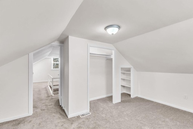 additional living space featuring light colored carpet and lofted ceiling