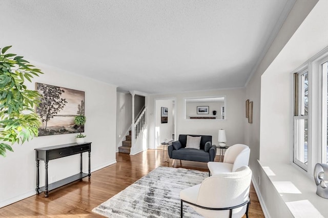 living room with wood-type flooring, a wealth of natural light, crown molding, and a textured ceiling