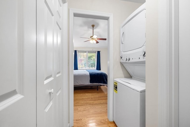 laundry room with laundry area, stacked washer and dryer, a ceiling fan, and light wood-type flooring