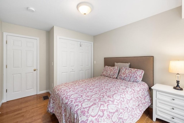 bedroom with a closet, visible vents, and wood finished floors