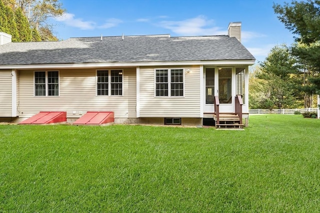 rear view of property with a shingled roof, a lawn, a chimney, and fence