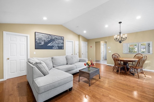 living room featuring baseboards, lofted ceiling, recessed lighting, light wood-type flooring, and a chandelier