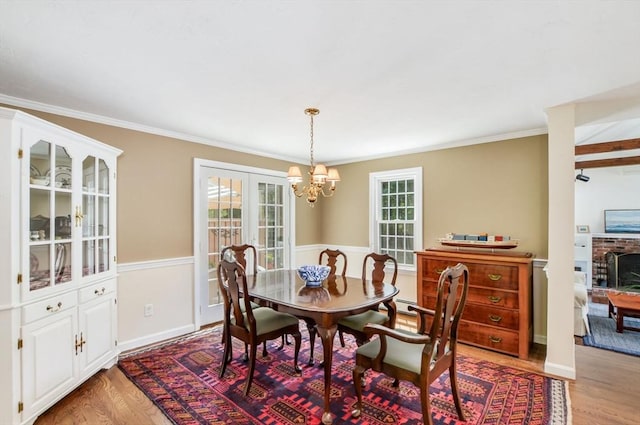 290 Cotuit Bay Dr, Barnstable, MA 02635 - dining area with light wood-type flooring, a chandelier, healthy amount of natural light, crown molding, and a fireplace