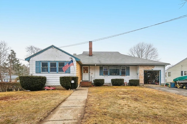 view of front of property featuring a front yard, driveway, a chimney, and an attached garage