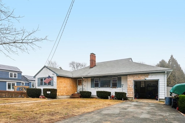 view of front facade with aphalt driveway, a shingled roof, a chimney, and a garage