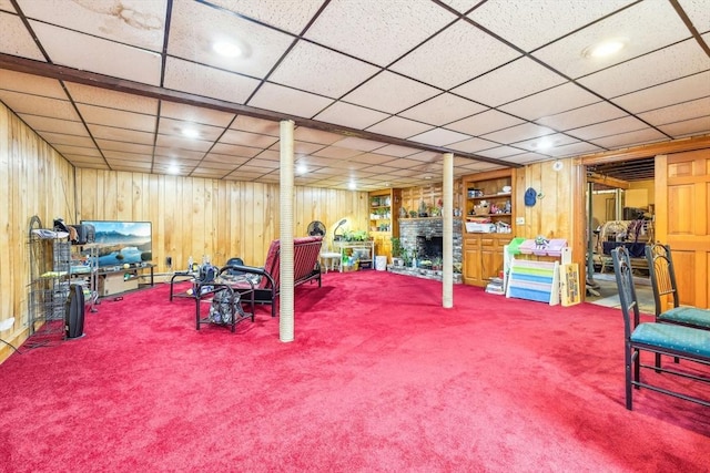 playroom with a large fireplace, wood walls, and carpet