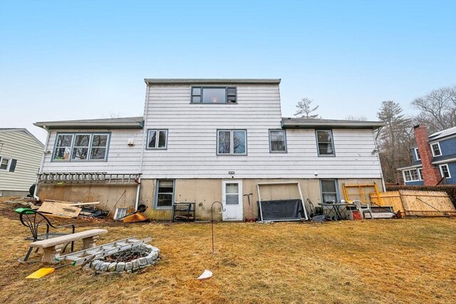 back of property with a fire pit, a yard, and fence