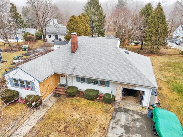 view of front of home with a front lawn, driveway, a chimney, and an attached garage