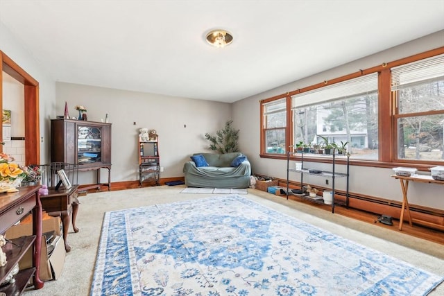 sitting room featuring a baseboard heating unit, carpet, and baseboards