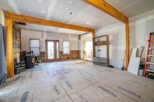 interior space featuring beamed ceiling and a wood stove