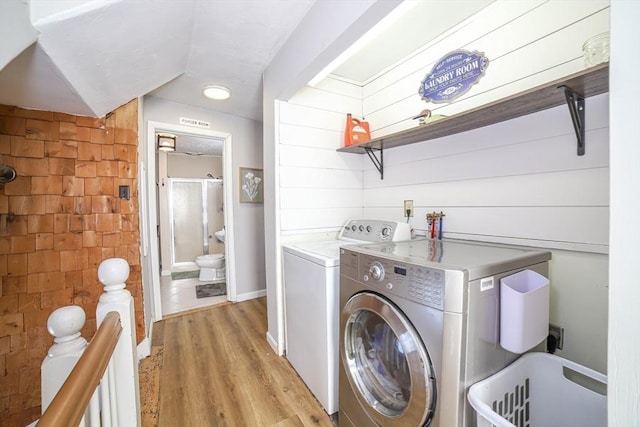 laundry room featuring washing machine and clothes dryer and light hardwood / wood-style floors