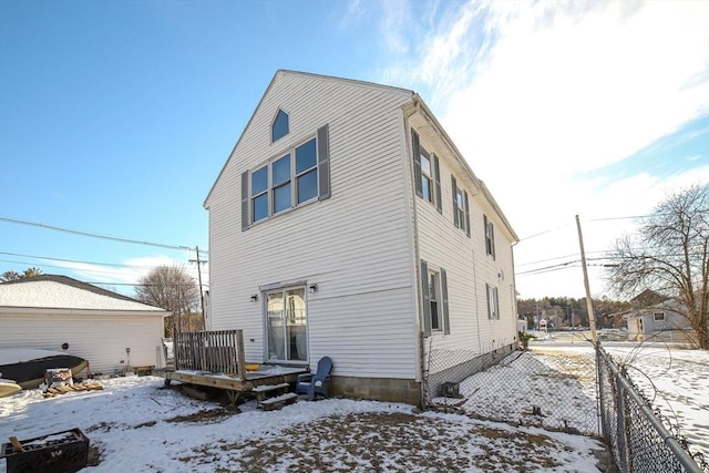 snow covered rear of property with a deck