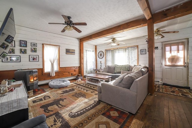 living room with dark hardwood / wood-style flooring, a baseboard heating unit, beam ceiling, and a wood stove