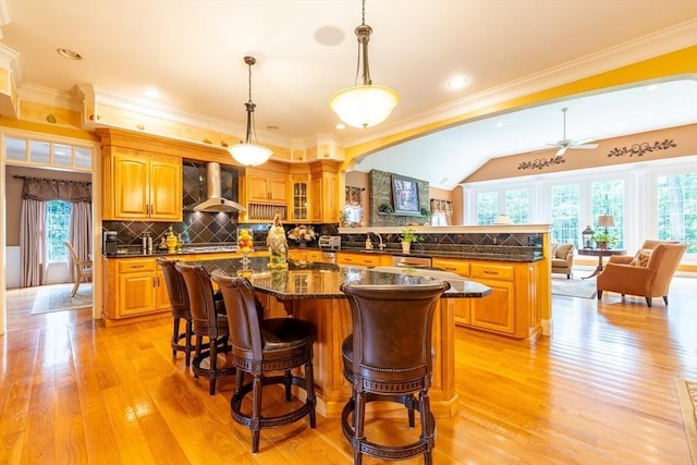 29 Hoveys Pond Dr, Boxford, MA 01921 - kitchen with wall chimney range hood, light wood-type flooring, tasteful backsplash, a center island, and a kitchen bar