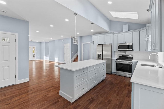 kitchen featuring stainless steel appliances, sink, decorative light fixtures, a center island, and dark hardwood / wood-style floors