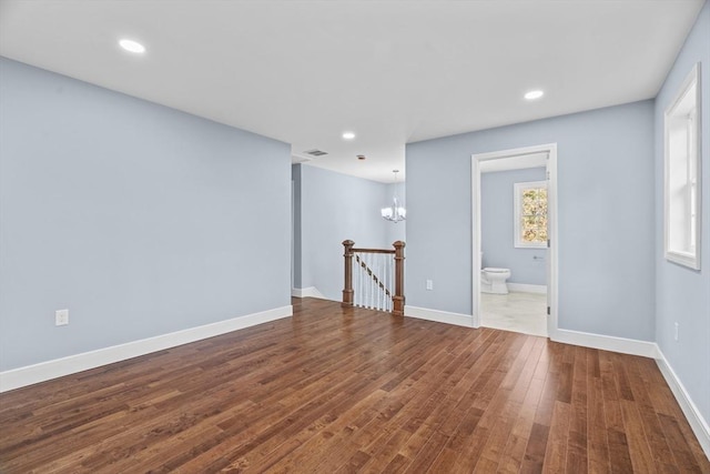 unfurnished room featuring hardwood / wood-style flooring and an inviting chandelier